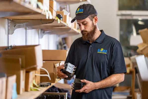 Kazar's Electric employee examining electrical components in a workshop, showcasing expertise in electrical contracting services.