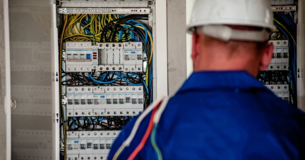 Electrician inspecting electrical panel with numerous wires and circuit breakers, emphasizing professional electrical installation services in Tampa.