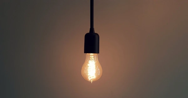 Hanging light bulb emitting warm glow, symbolizing energy conservation and efficient lighting solutions for reducing electricity usage.