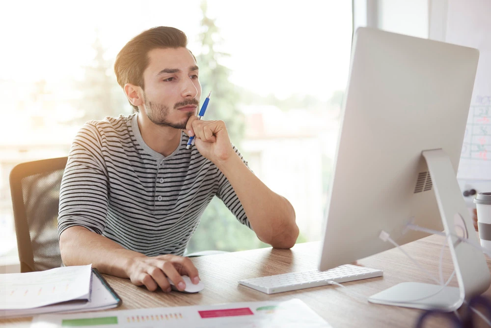 Man contemplating at a desk with a computer, reflecting on how to choose a reputable electrical contractor for home projects.