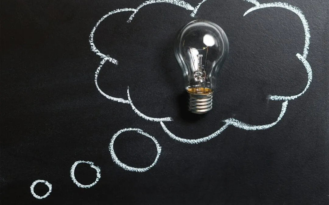 Light bulb surrounded by chalk thought bubbles on a black background, symbolizing ideas related to electrical work and the importance of safety in DIY versus professional services.