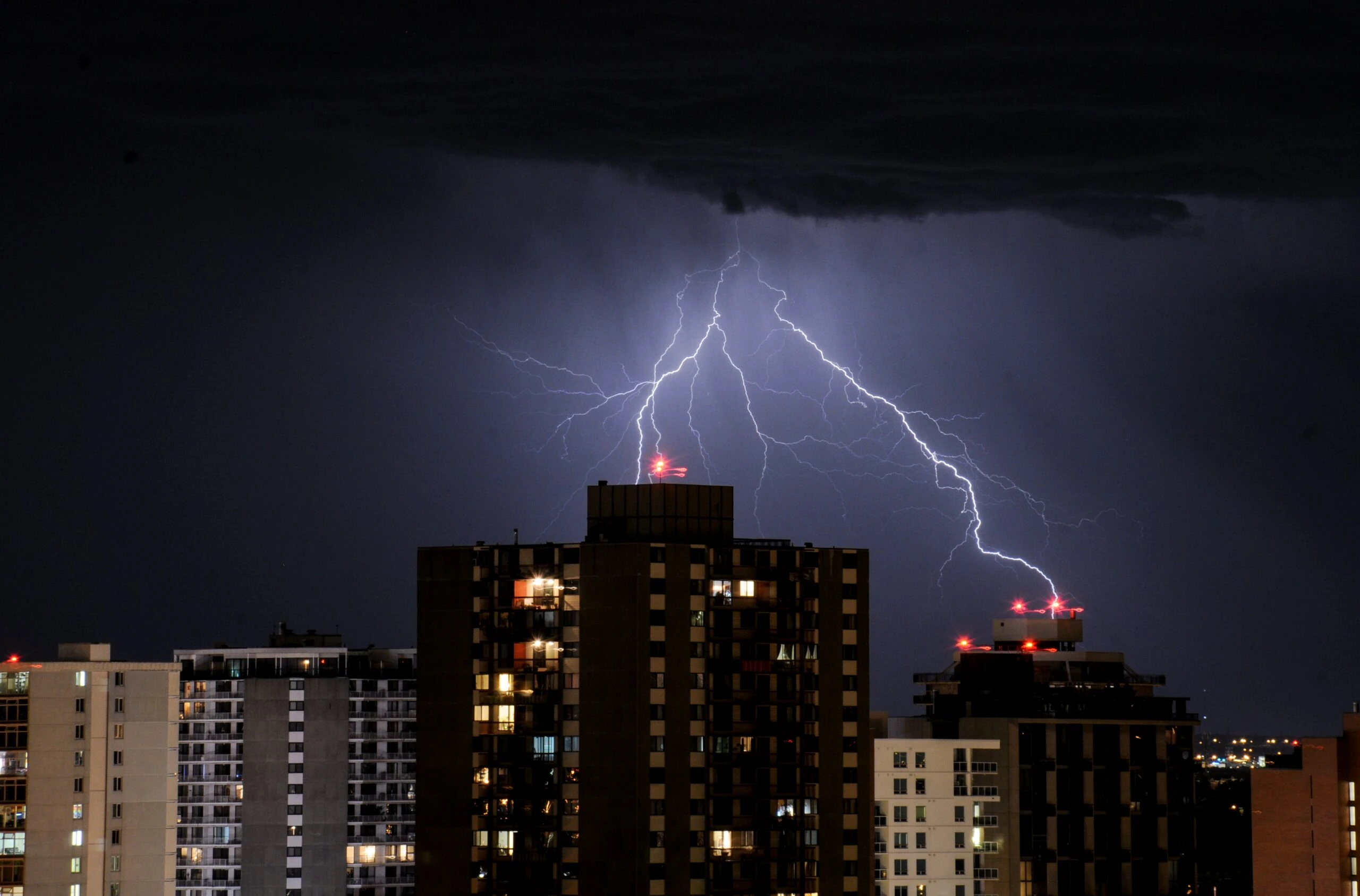 Lightning striking buildings at night, illustrating the risks of electrical surges and the importance of lightning arresters for protection.